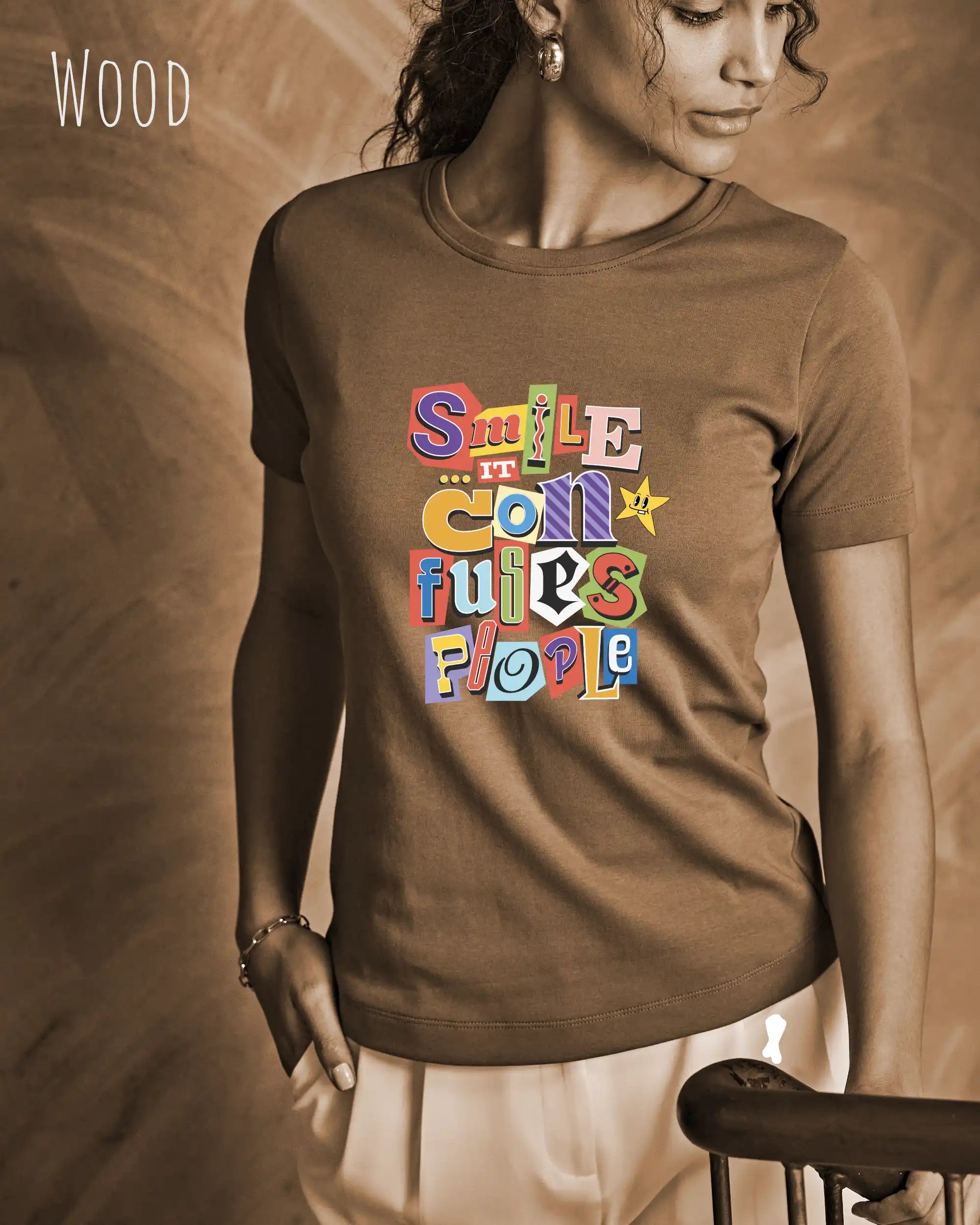 Die Abbildung zeigt eine frau, die ein feminines design-t-shirt in der farbe wood mit der farbenfrohen grafik "smile ... it confuses people" trägt.
