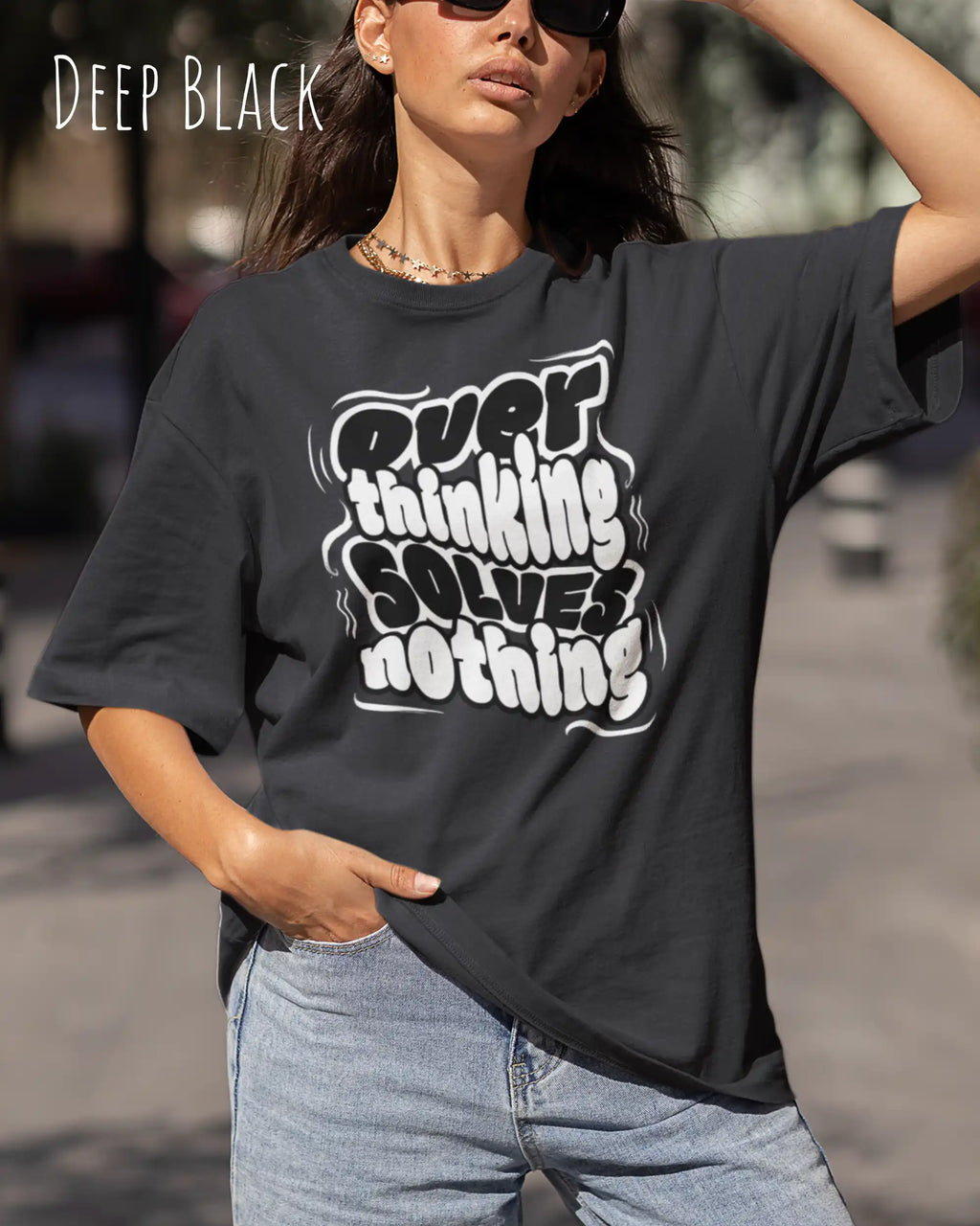 Frau  trägtt ein oversized heavyweight t-shirt in  deep black mit dem design overthinking solves nothing.