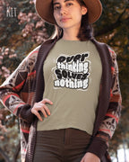diese Abbildung zeigt eine frau, die ein feminines design-t-shirt in der farbe kit mit dem ausdrucksstarken design "overthinking solves nothing" trägt.
