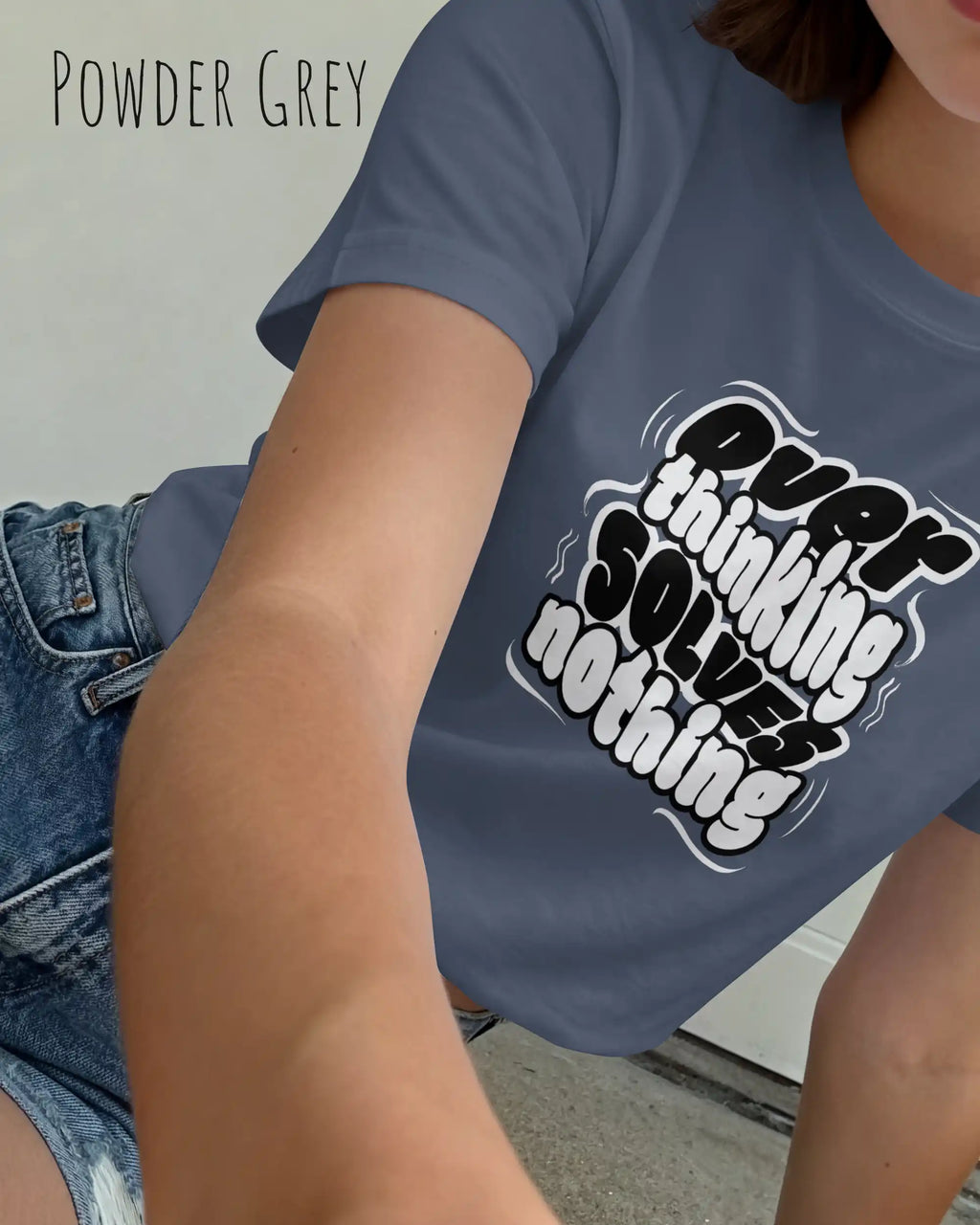 diese Abbildung zeigt eine frau, die ein feminines design-t-shirt in der farbe powder grey mit dem ausdrucksstarken design "overthinking solves nothing" trägt.