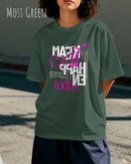 junge Frau trägtt ein oversized heavyweight t-shirt in moss green mit dem design make it happen today.