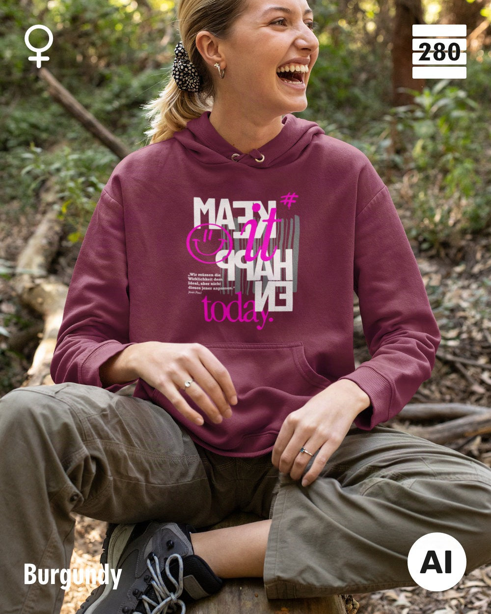 das bild zeigt eine lachende frau, die einen ldamen hoodie in der farbe burgundy und mit dem statement design "make it happen today" trägt.