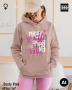 das bild zeigt eine frau, die einen leicht taillierten damen hoodie in der farbe dusty pink und mit dem statement design "make it happen today" trägt.