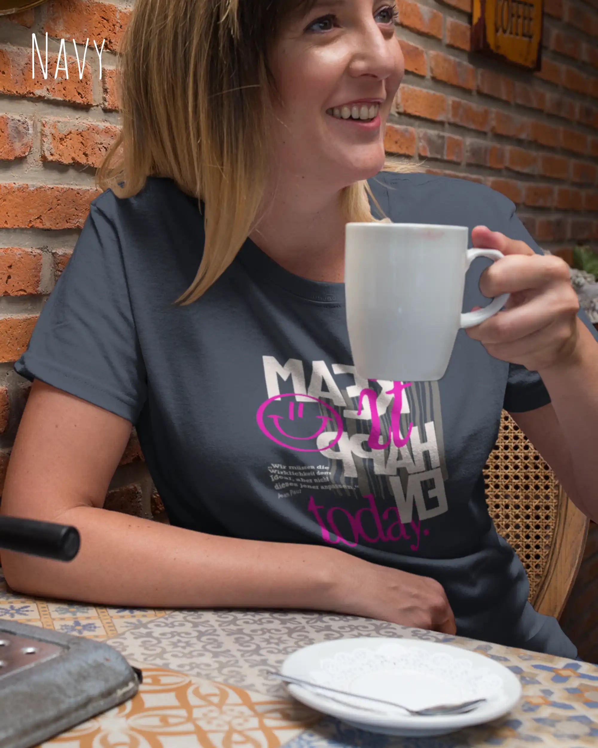 frau im cafe trägt ein design t-shirt in der farbe navy mit dem motiv make it happen today.