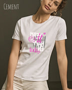 das bild zeigt eine frau, die ein design-t-shirt in der farbe cement mit dem inspirierenden motiv "make it happen today" trägt,