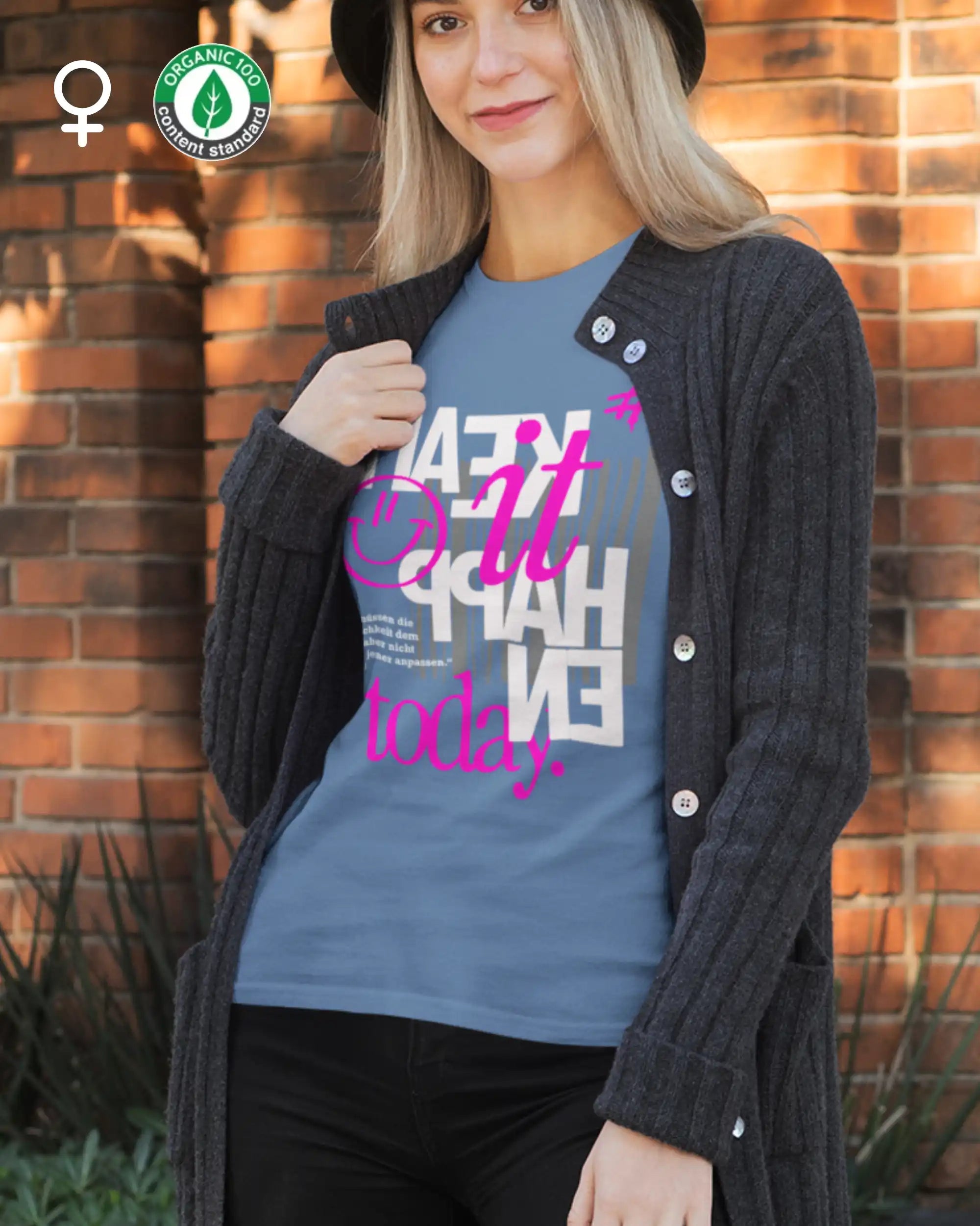 das bild zeigt eine blonde junge frau, die ein feminines design-t-shirt aus bio baumwolle mit dem inspirierenden motiv "make it happen today" trägt,
