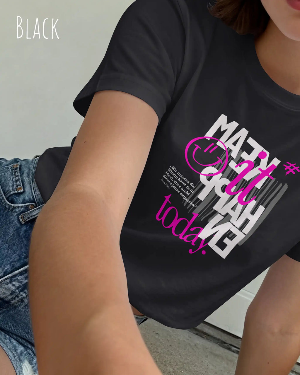 das bild zeigt eine frau, die ein feminines design-t-shirt in der farbe black mit dem inspirierenden motiv "make it happen today" trägt,