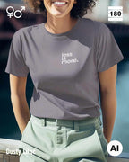 Das bild zeigt eine frau, die ein Unisex Design-T-Shirt in der farbe dusty lilac mit dem minimalistischen motiv "less is more" trägt.