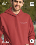 das bild zeigt eine person, die einen unisex design hoodie in der farbe brick red und mit dem zeitlosen motiv "less is more" trägt.