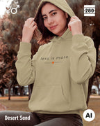 das bild zeigt eine frau, die einen unisex design hoodie in der farbe desert sand und mit dem zeitlosen motiv "less is more" trägt.