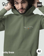 das bild zeigt eine person, die einen unisex design hoodie in der farbe earthy green und mit dem zeitlosen motiv "less is more" trägt.
