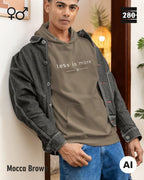 das bild zeigt eine person, die einen unisex design hoodie in der farbe mocca brown und mit dem zeitlosen motiv "less is more" trägt.