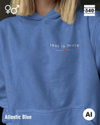 Eine frau trägt einen Oversized Design-Hoodie unisex in der farbe atlantic blue  mit dem zeitlosen statement "less is more" oben links.