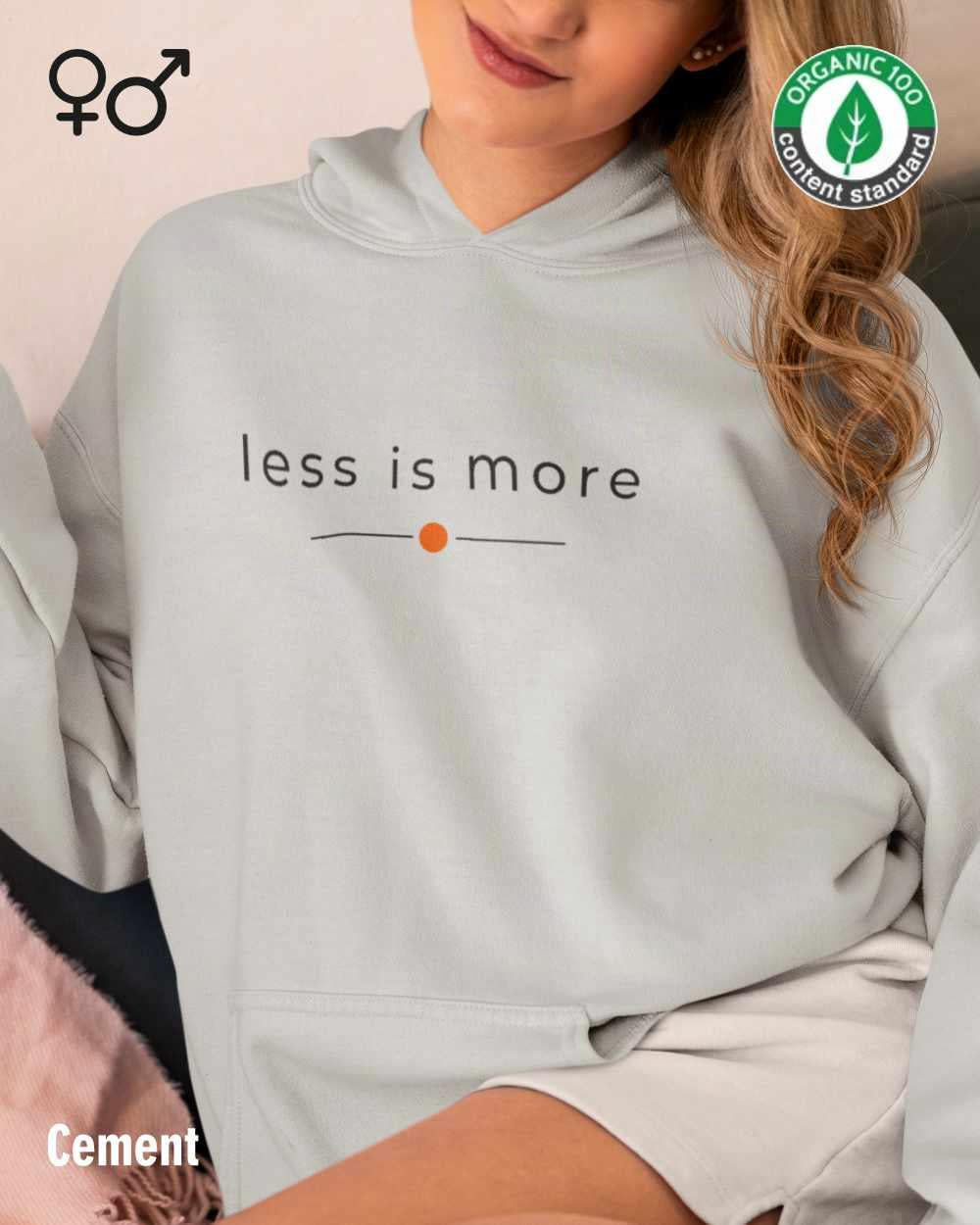 eine frau trägt einen Premium Design-Hoodie aus 100% Bio-Baumwolle in der farbe cement mit dem eleganten motiv "less is more" mittig auf der brust..