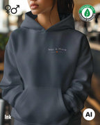 eine frau trägt einen Premium Design-Hoodie aus 100% Bio-Baumwolle in der farbe ink mit dem eleganten motiv "less is more" oben links.
