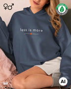 eine frau trägt einen Premium Design-Hoodie aus 100% Bio-Baumwolle in der farbe ink mit dem eleganten motiv "less is more" .