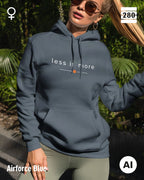 das bild zeigt eine frau, die einen leicht taillierten damen hoodie in der farbe airforce blue und mit dem zeitlosen design "less is more" trägt.