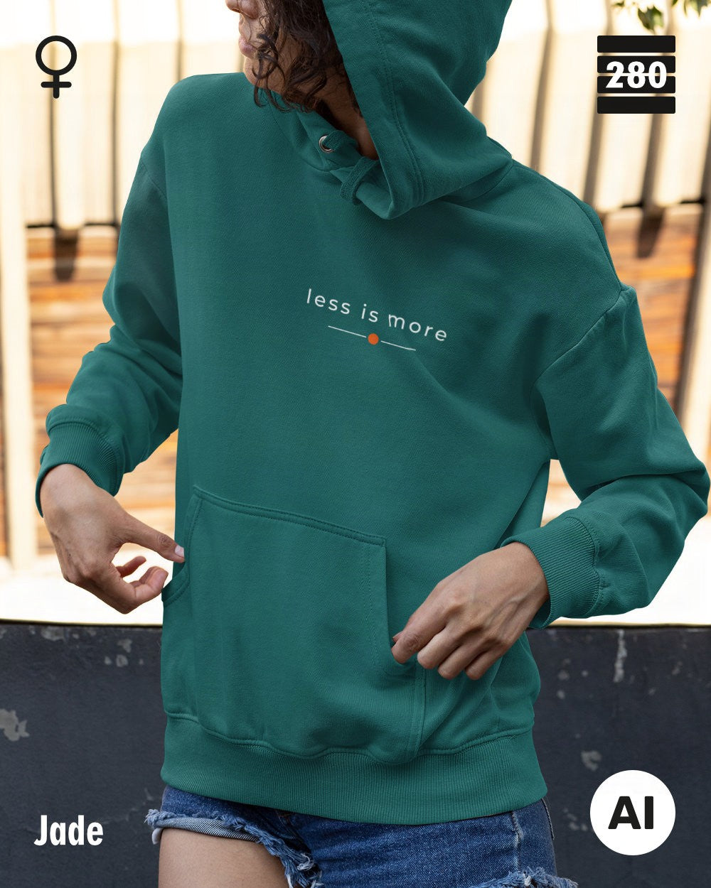das bild zeigt eine frau, die einen leicht taillierten damen hoodie in der farbe jade und mit dem zeitlosen design "less is more" trägt.