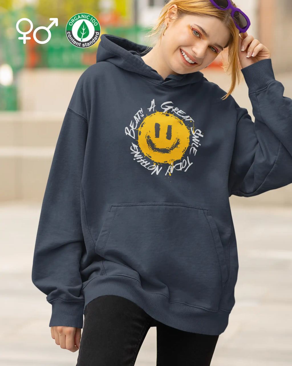 Eine junge frau trägt einen unisex design-hoodie aus bio-baumwollen mit einem fröhlichen smiley-motiv.